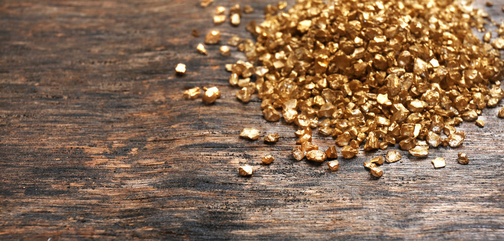 A pile of gold pieces on a wooden background. Post gold for cash amounts.