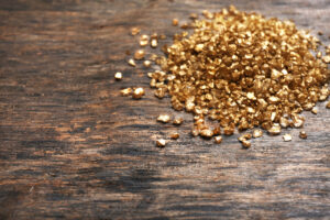 A pile of gold pieces on a wooden background. Post gold for cash amounts.