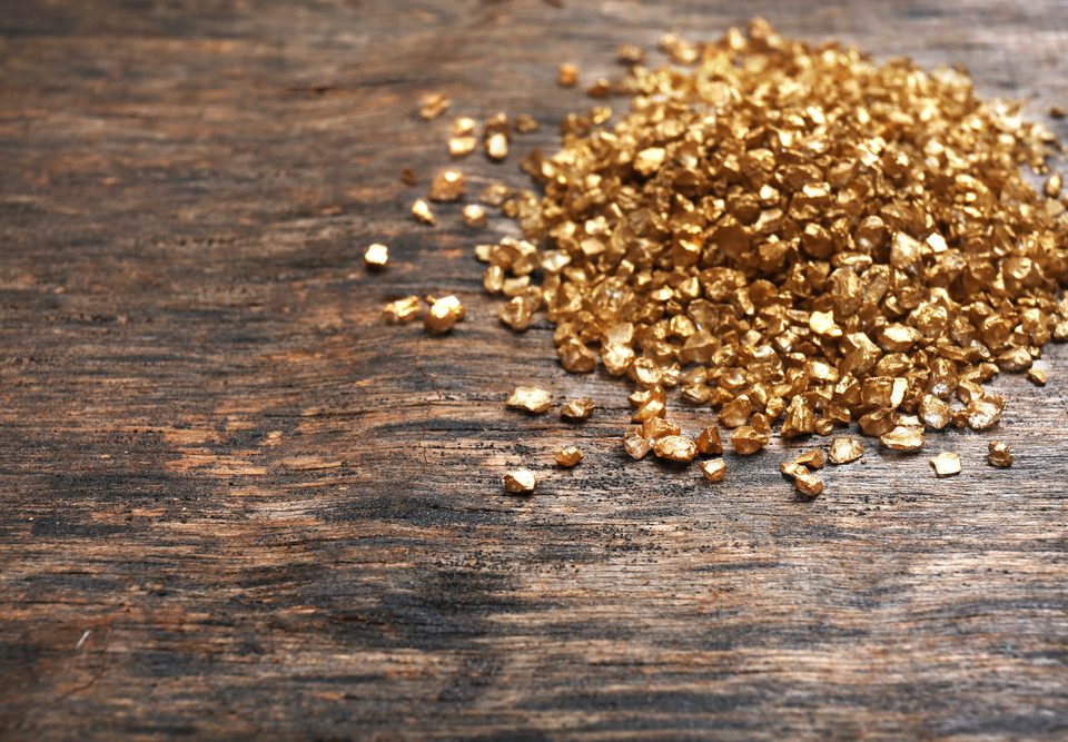 A pile of gold pieces on a wooden background. Post gold for cash amounts.