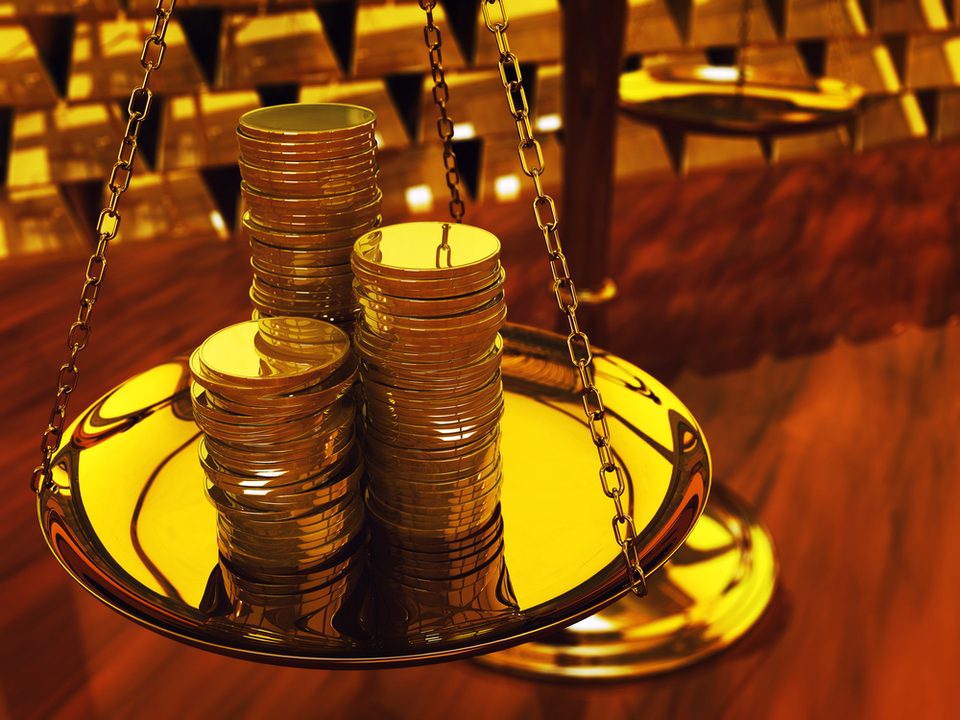 A stack of rare gold coins on a gold weighing scale