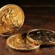 Three gold sovereign coins on a mahogany table